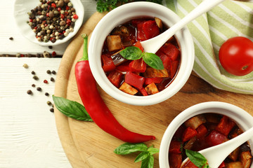 Tasty vegetarian ratatouille made of eggplants, squash, tomatoes in bowls on wooden table background