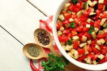 Ratatouille before cooking and ingredients, on wooden background