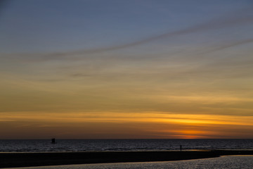 Fototapeta na wymiar Black silhouettes on a beach in a colorful orange sky sunset landscape in Africa.