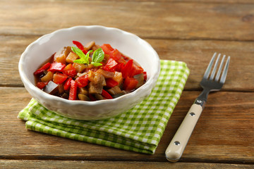 Ratatouille in bowl, on wooden table background