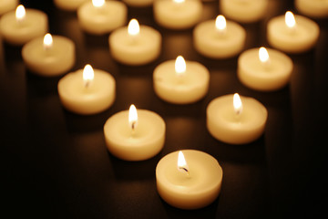 Fototapeta na wymiar Alight candles in a row on black background