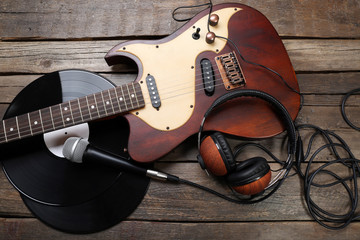 Naklejka premium Electric guitar and headphones with microphone and vinyl on wooden background
