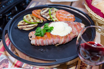 Rolled pork meat with grill vegetables on metal plate