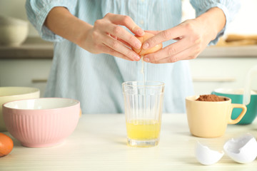 Woman is breaking an egg into a glass