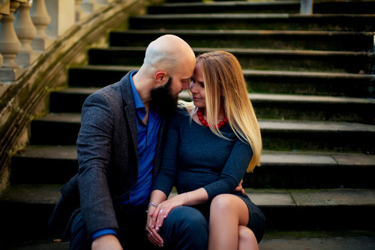 happy couple in love with each other,One beautiful stylish couple of young woman and senior man with long black beard   embracing close to each other outdoor in autumn street on stairs sunny day