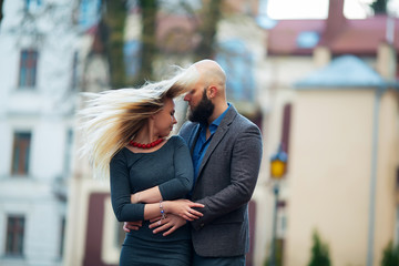 happy couple in love with each other,One beautiful stylish couple of young woman and senior man with long black beard   embracing close to each other outdoor in autumn street on stairs sunny day