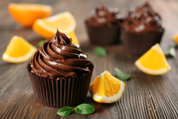 Chocolate cupcakes served with orange and mint on a table