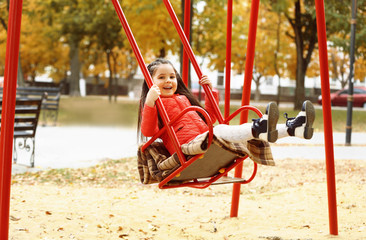 Little girl on swing in city park