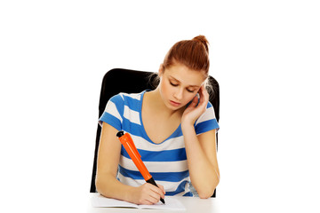 Pensive teenage woman doing homework