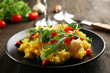 Black plate with vegetable risotto on served wooden table