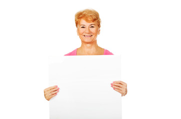 Fototapeta premium Smiling senior woman holding empty banner