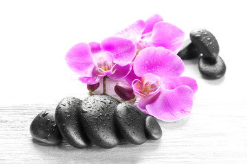 Beautiful composition of orchid and pebbles on white wooden background, close up