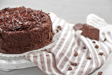 Tasty chocolate cake on wooden table, on light background