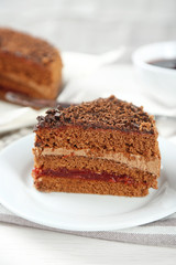 Sliced chocolate cake on plate, on wooden table  background