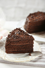 Sliced chocolate cake on wooden table, on light background