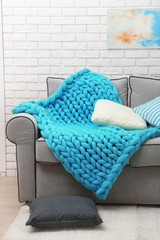 Knitted woolen blanket on sofa, on home interior background