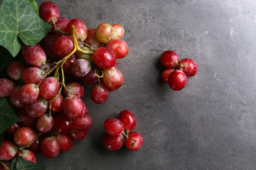 Bunch of grape with green leaves on grey background, copy space