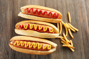 Tasty hot-dogs with French fries on wooden background