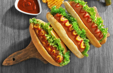 Tasty hot-dogs with chips on wooden background