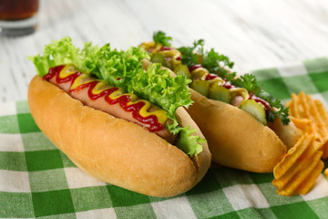 Delicious hot-dogs with chips on green checkered cotton napkin, close up