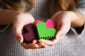 Closeup of plastic puzzle hearts in female hands