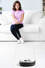 Cleaning concept - automatic robotic hoover clean the room while woman relaxing, close up