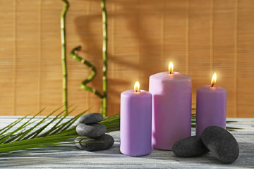 Purple candles with spa stones and bamboo on table