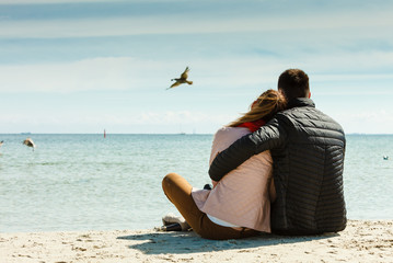 couple sitting on beach rear view