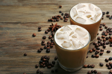 Two cups of ice coffee with coffee beans on wooden table