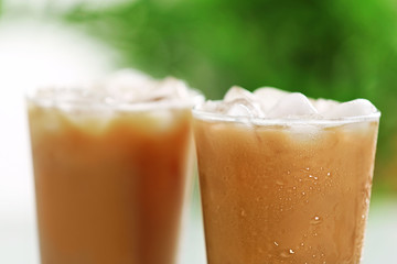 Cups of ice coffee on light blurred background