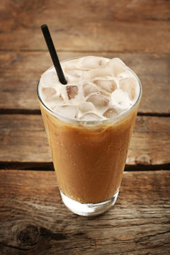 Cup of ice coffee with straw on wooden background