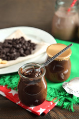 Chocolate dessert in small glass jars and morsels on plate, on wooden background