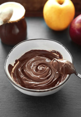 Melted chocolate in bowl, on wooden background