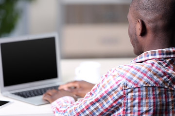 Handsome businessman with laptop in his office, backside view