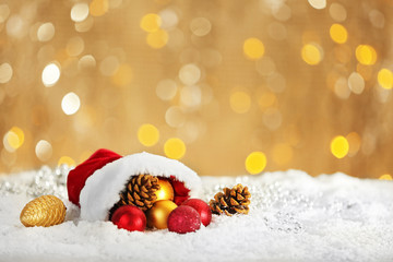 Fototapeta na wymiar Christmas decorations in red Santa hat on shiny background, close up