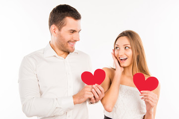 Fototapeta na wymiar Cheerful couple in love holding red paper hearts