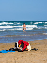 Objetos de playa y mujer bañándose, Playa de Gandia, Valencia, España