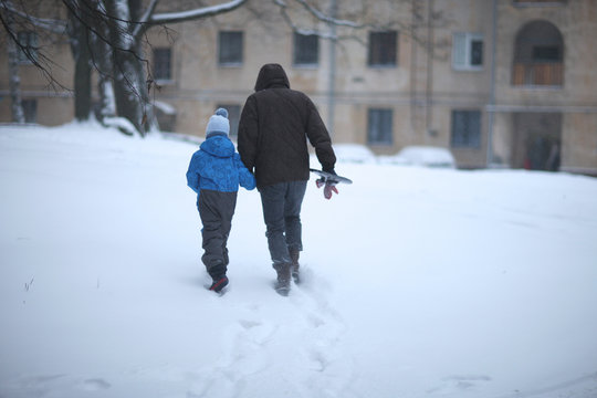 Rear View Of Father And Son Walking In The Snow