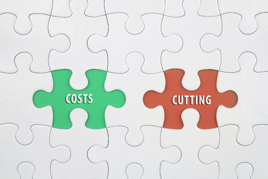 Jigsaw puzzle on color paper background with a word COSTS and CUTTING
