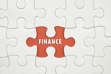 Fototapeta premium Jigsaw puzzle on color paper background with a word FINANCE
