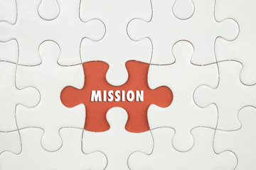 Fototapeta premium Jigsaw puzzle on color paper background with a word MISSION