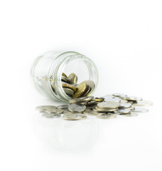 Coins spilling out of a jar over white background