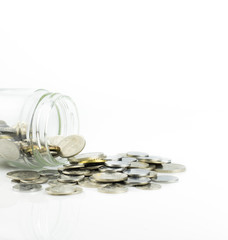 Coins spilling out of a jar over white background