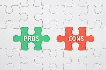 Jigsaw puzzle on color paper background with a word PROS and CONS
