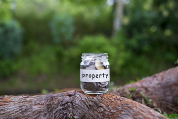 Fototapeta premium Coins in glass with Property label against bokeh background.Financial concept.Selective focus.