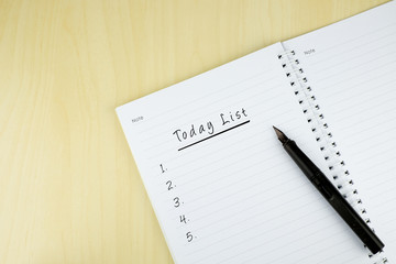 "Today List" is written on notepad with pen on office table. Top View