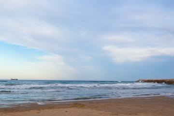 Sandy beach near Valencia, Spain. A beautiful beach with shallow water and a stony breakwater pier.