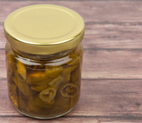 Pickled chili in mason jar over wooden background