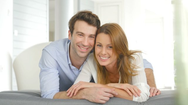 Portrait of cheerful couple laying on cushion