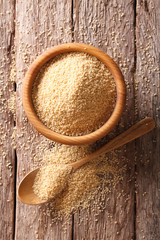 Raw Couscous in a wooden bowl and spoon. vertical top view
